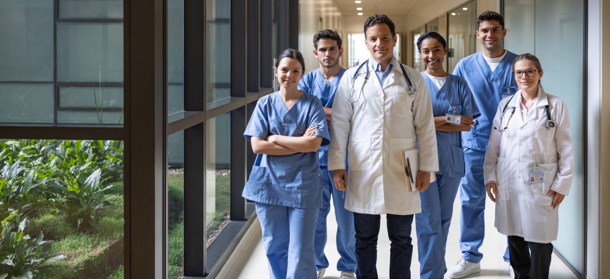 Happy Latin American team of doctors and nurses working at the hospital and looking at the camera smiling - healthcare and medicine concepts